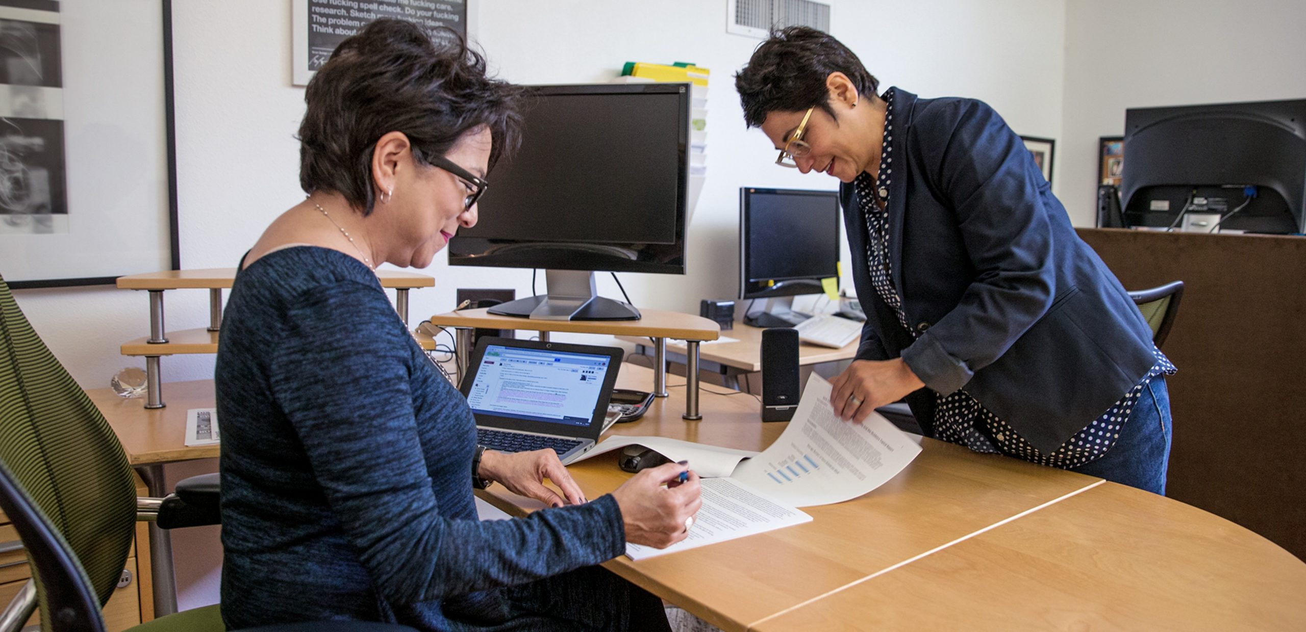 Two women working at a desk in an office.