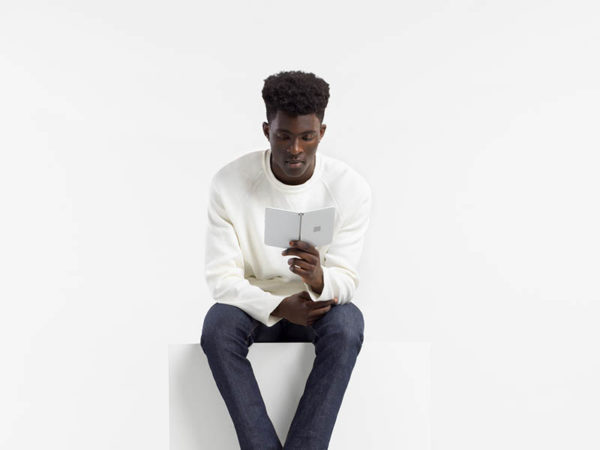 Seated man holding a Surface Duo