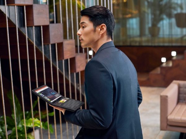 Asian man with his back to camera holds Lenovo ThinkPad X1 Fold in his left hand