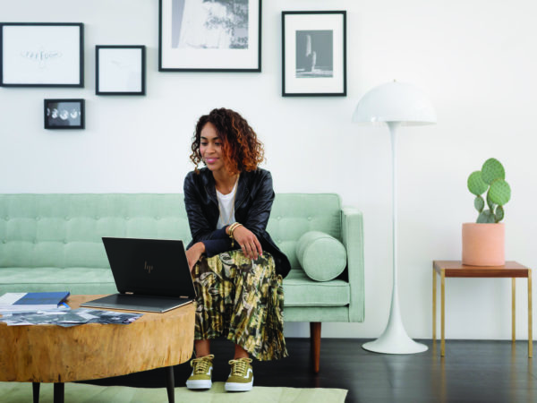 HP Spectre x360 14 on a table facing a woman on a green couch