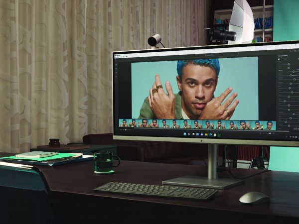 Man in front of a blue screen with HP Envy 34 AIO in foreground