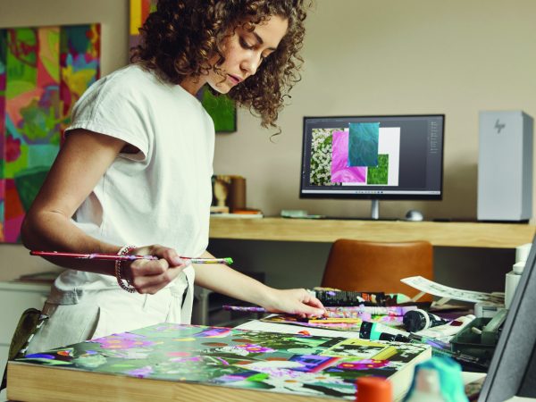 Woman looking over art with HP laptop in background